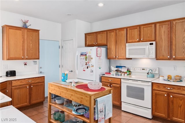 kitchen with white appliances, light tile patterned floors, light countertops, brown cabinetry, and recessed lighting