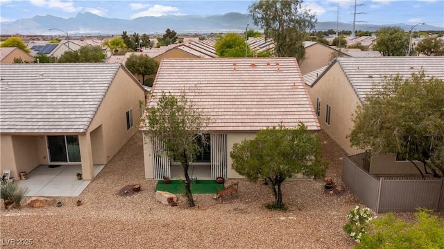 rear view of property featuring stucco siding, fence, a patio area, a mountain view, and a residential view