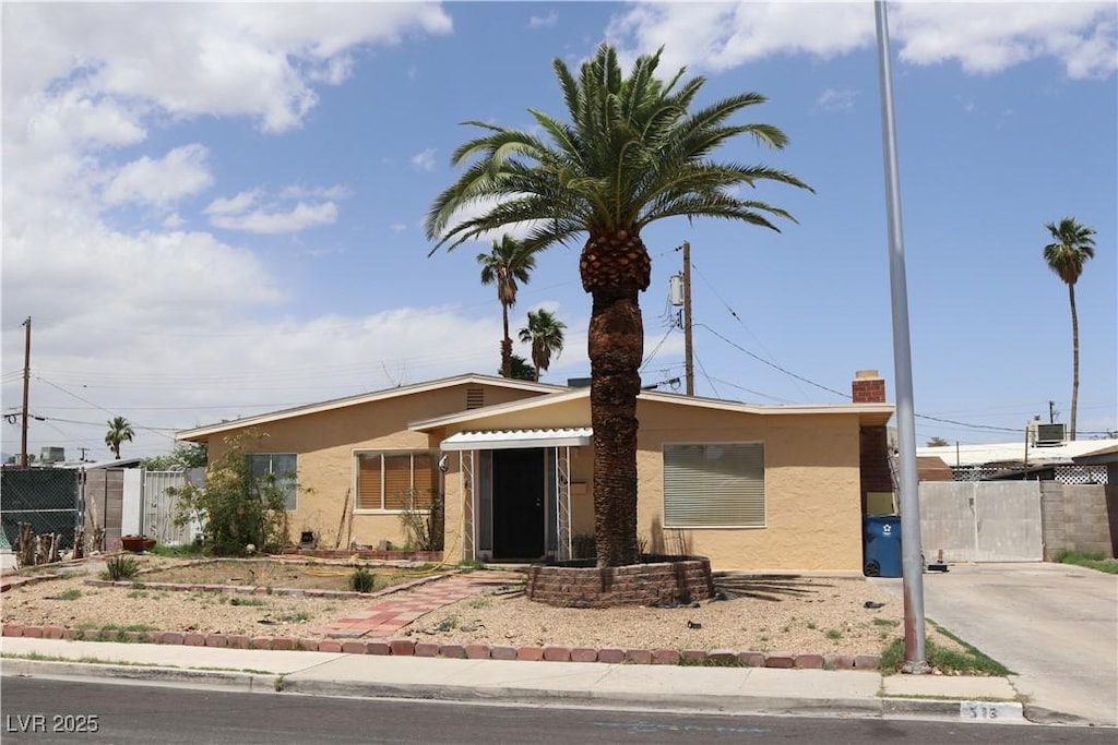 view of front facade featuring stucco siding, a gate, and fence