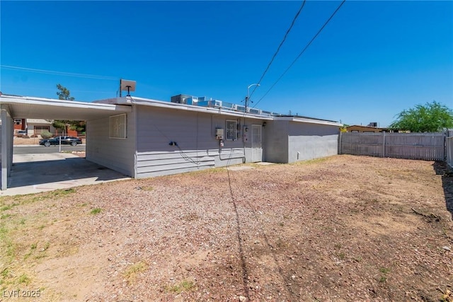 rear view of property with an attached carport and fence