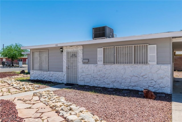view of front facade featuring central AC unit and stone siding