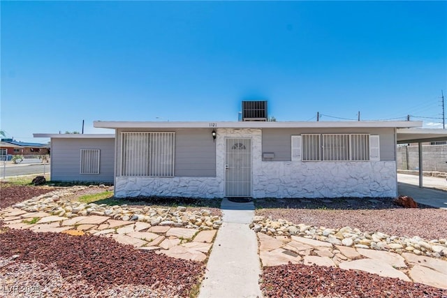 view of front of property with central air condition unit, an attached carport, and stone siding