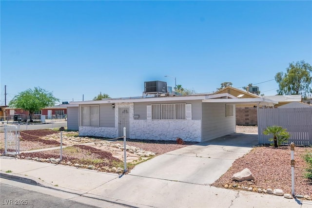 single story home featuring fence, a carport, concrete driveway, and central AC