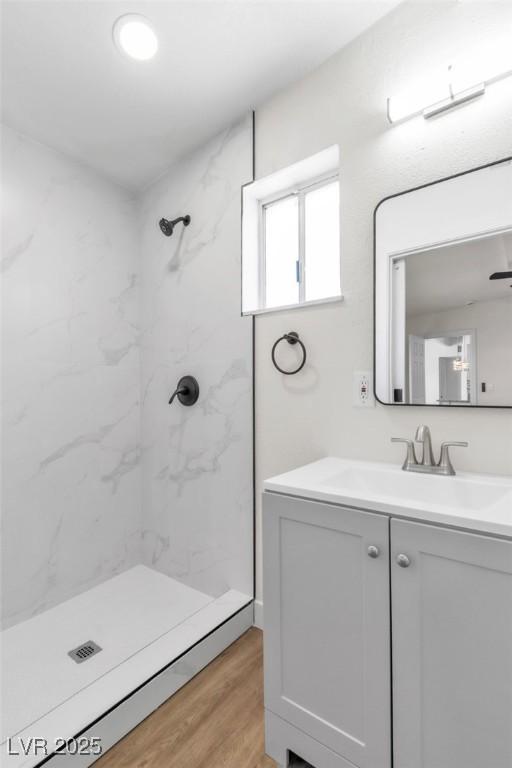 bathroom with a marble finish shower, vanity, and wood finished floors