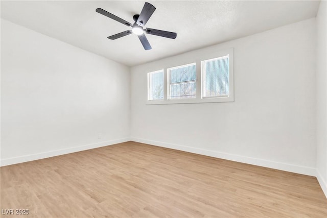 spare room with baseboards, light wood-type flooring, and a ceiling fan
