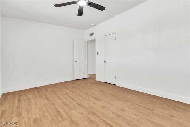 empty room with ceiling fan, light wood-style flooring, and baseboards