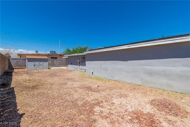 fenced backyard with a storage shed and an outdoor structure