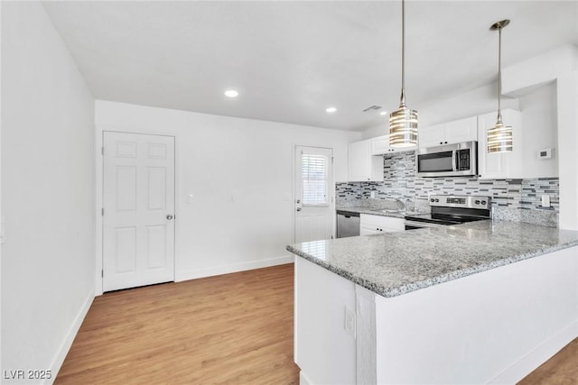 kitchen featuring stainless steel appliances, white cabinets, tasteful backsplash, light stone counters, and light wood-type flooring