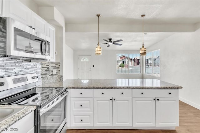 kitchen featuring stainless steel appliances, a ceiling fan, decorative backsplash, a peninsula, and light wood-style flooring