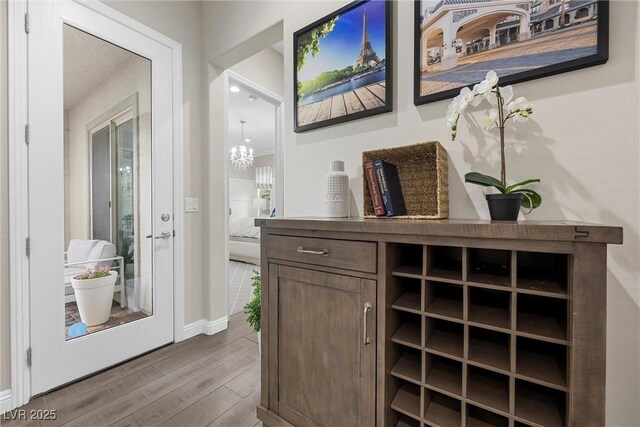 4220 San Alivia Ct, Las Vegas, NV 89141 - bar featuring wood finished floors, a chandelier, and baseboards