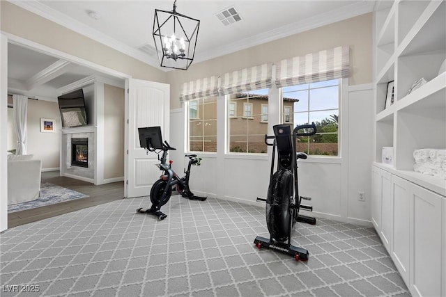 4220 San Alivia Ct, Las Vegas, NV 89141 - exercise room featuring light colored carpet, ornamental molding, a glass covered fireplace, a chandelier, and baseboards