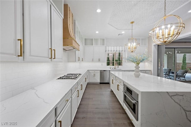 4220 San Alivia Ct, Las Vegas, NV 89141 - kitchen featuring a chandelier, appliances with stainless steel finishes, custom range hood, a sink, and white cabinetry
