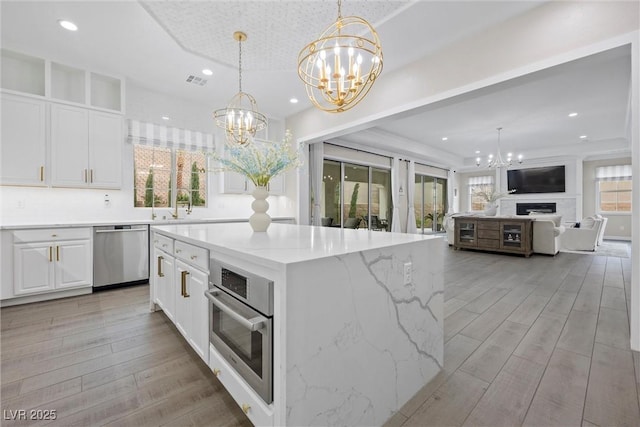 4220 San Alivia Ct, Las Vegas, NV 89141 - kitchen with appliances with stainless steel finishes, a chandelier, recessed lighting, white cabinetry, and light stone countertops