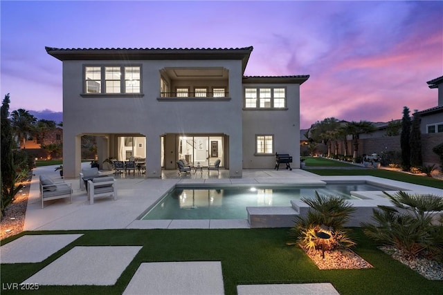 4220 San Alivia Ct, Las Vegas, NV 89141 - back of property at dusk featuring a patio, an outdoor pool, a tiled roof, stucco siding, and a lawn