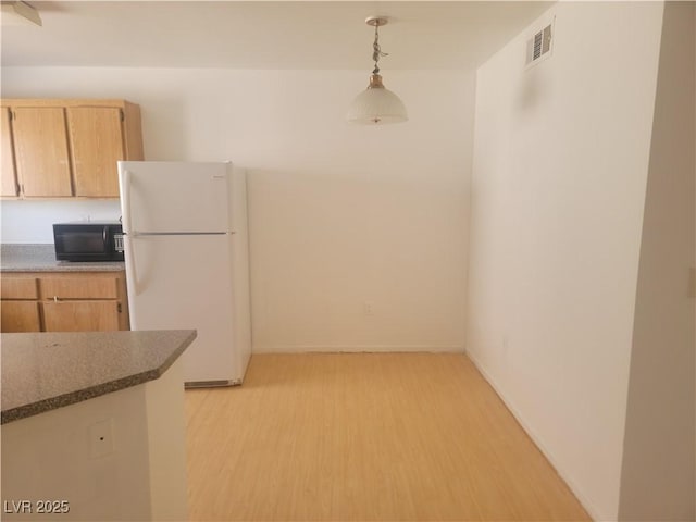 3965 Rebecca Raiter Ave Unit 201, Las Vegas, NV 89110 - kitchen with freestanding refrigerator, black microwave, light wood-type flooring, decorative light fixtures, and light brown cabinets