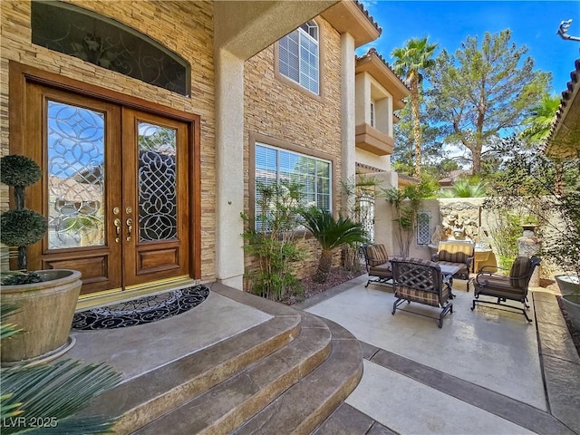 5445 Pendini Point Ct, Las Vegas, NV 89141 - entrance to property with french doors, stone siding, a patio, an outdoor hangout area, and stucco siding