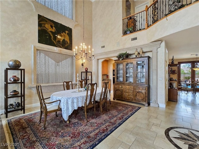 5445 Pendini Point Ct, Las Vegas, NV 89141 - dining area featuring a chandelier, a towering ceiling, baseboards, arched walkways, and stone tile flooring