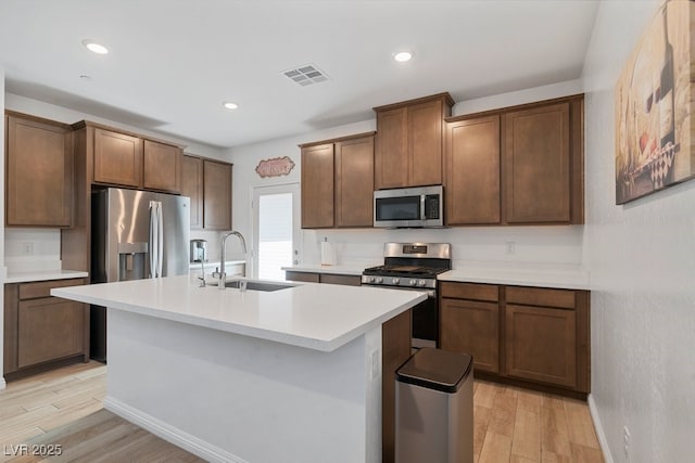 3709 Neblina Dr, Henderson, NV 89052 - kitchen featuring appliances with stainless steel finishes, a sink, light wood-style floors, an island with sink, and recessed lighting