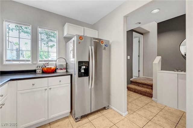 9065 Adorable Ave, Las Vegas, NV 89149 - kitchen with stainless steel fridge, dark countertops, white cabinets, light tile patterned floors, and light colored carpet