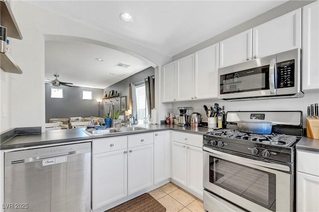 9065 Adorable Ave, Las Vegas, NV 89149 - kitchen featuring appliances with stainless steel finishes, ceiling fan, white cabinetry, arched walkways, and light tile patterned floors