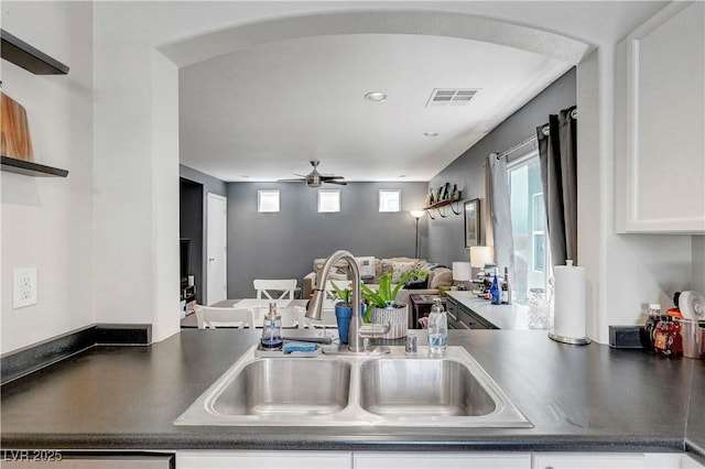 9065 Adorable Ave, Las Vegas, NV 89149 - kitchen with a sink, dark countertops, arched walkways, white cabinetry, and ceiling fan