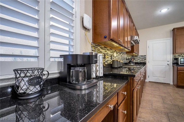 7520 Fontera Ct, Las Vegas, NV 89139 - kitchen featuring backsplash, dark stone counters, brown cabinets, exhaust hood, and recessed lighting