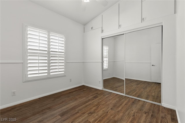 unfurnished bedroom featuring wood finished floors, a closet, lofted ceiling, baseboards, and ceiling fan