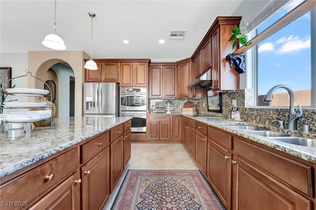 7778 Villa Montara St, Las Vegas, NV 89123 - kitchen with a sink, appliances with stainless steel finishes, tasteful backsplash, light stone countertops, and arched walkways