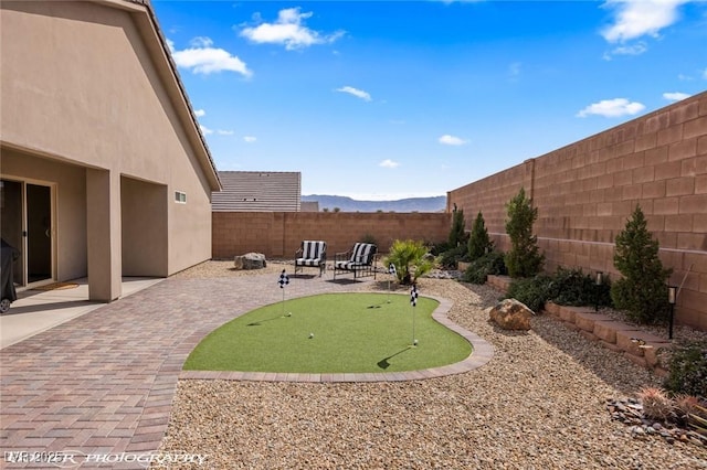 942 Shadow Hawk Rdg, Mesquite, NV 89027 - fenced backyard with a putting area, a patio, and a mountain view