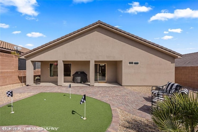 942 Shadow Hawk Rdg, Mesquite, NV 89027 - rear view of house with an area to practice putting, a patio, stucco siding, and fence