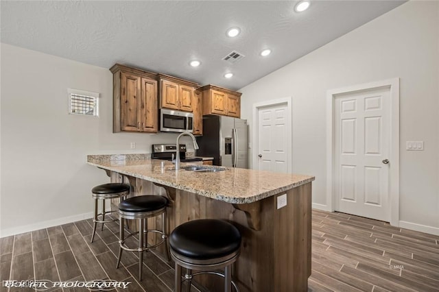 942 Shadow Hawk Rdg, Mesquite, NV 89027 - kitchen featuring appliances with stainless steel finishes, wood finish floors, a breakfast bar area, a sink, and lofted ceiling