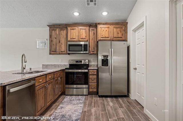 942 Shadow Hawk Rdg, Mesquite, NV 89027 - kitchen with appliances with stainless steel finishes, a sink, a peninsula, dark wood-type flooring, and brown cabinetry