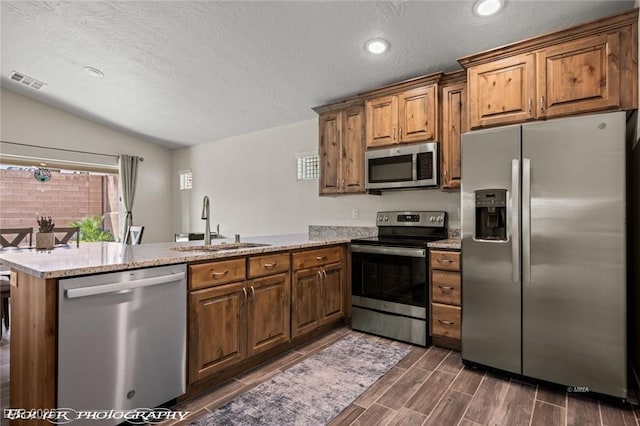 942 Shadow Hawk Rdg, Mesquite, NV 89027 - kitchen with stainless steel appliances, a sink, a peninsula, lofted ceiling, and brown cabinetry