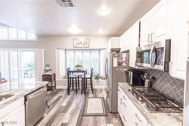 53 Grossinger Ct, Henderson, NV 89074 - kitchen with appliances with stainless steel finishes, light wood-type flooring, decorative backsplash, and white cabinetry