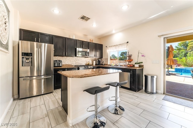 kitchen with appliances with stainless steel finishes, healthy amount of natural light, a kitchen island, decorative backsplash, and recessed lighting