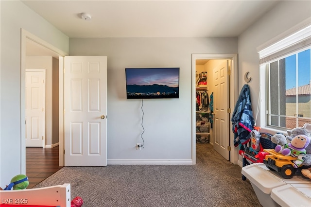bedroom featuring a walk in closet, carpet floors, baseboards, and a closet