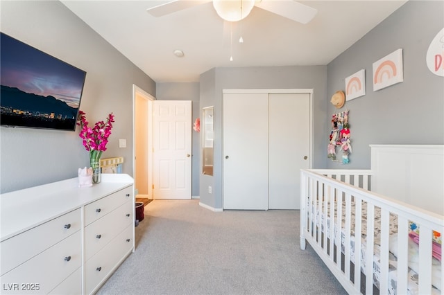 bedroom featuring a closet, light colored carpet, a ceiling fan, a nursery area, and baseboards