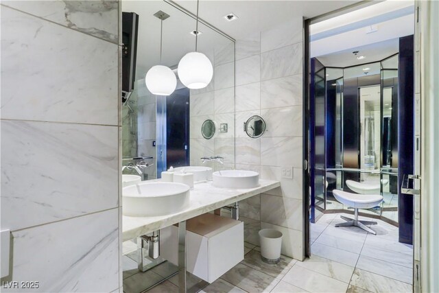 4381 W Flamingo Rd Unit 2122, Las Vegas, NV 89103 - bathroom featuring tile walls, a sink, and marble finish floors