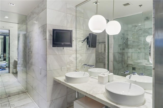 bathroom with tile walls, a stall shower, and double vanity