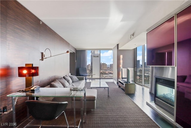 living room featuring a wall of windows, plenty of natural light, a multi sided fireplace, and wood finished floors