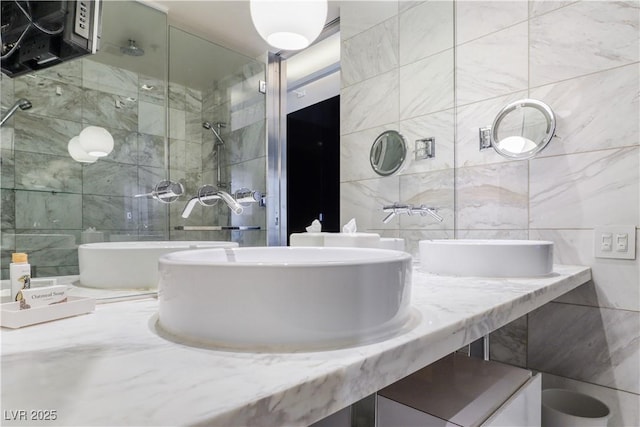 bathroom with tile walls, a shower stall, and double vanity