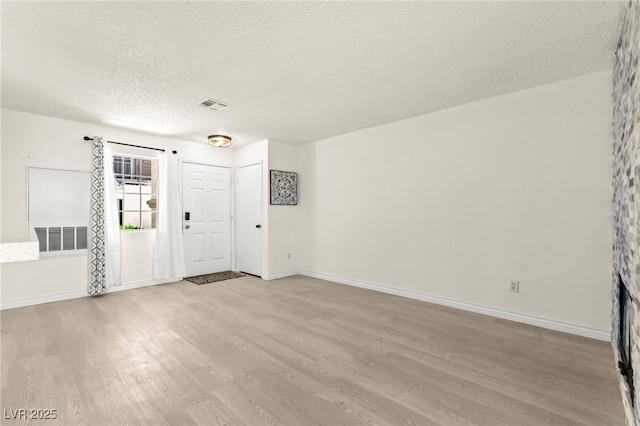 foyer entrance featuring light wood-style floors, a textured ceiling, and baseboards
