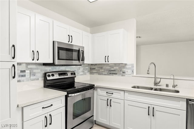 kitchen with stainless steel appliances, a sink, white cabinets, and backsplash