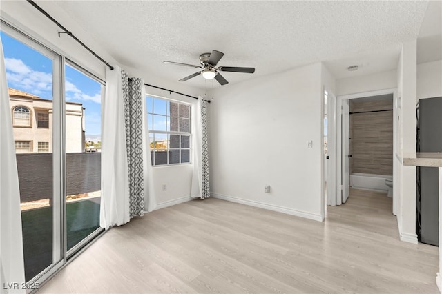 unfurnished bedroom featuring a textured ceiling, light wood-type flooring, baseboards, and ceiling fan