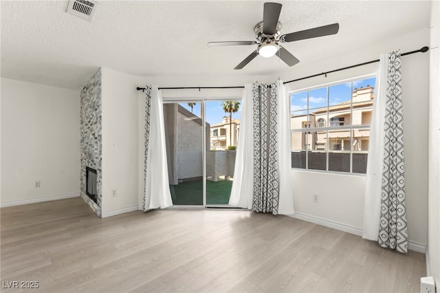 spare room with wood finished floors, ceiling fan, baseboards, and a textured ceiling