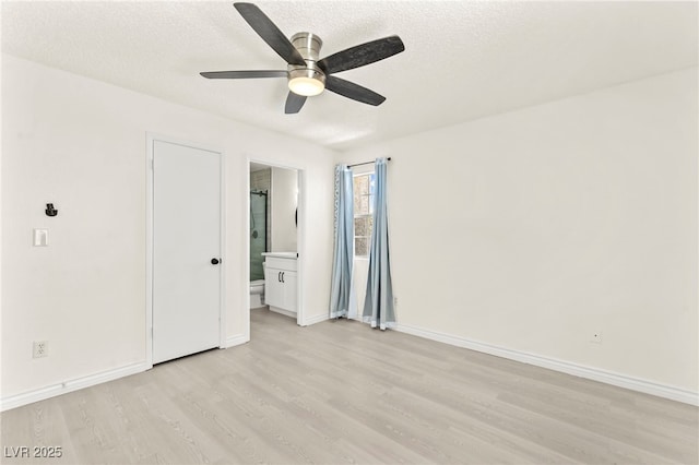 unfurnished bedroom featuring light wood finished floors, baseboards, a textured ceiling, ensuite bathroom, and a ceiling fan