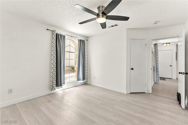 empty room featuring ceiling fan, light wood finished floors, a textured ceiling, baseboards, and a smoke detector