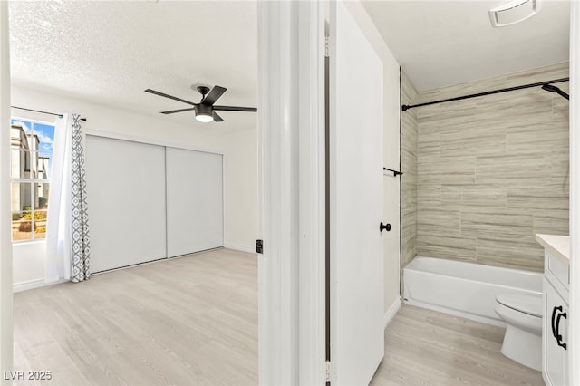 full bath featuring wood finished floors, toilet, a ceiling fan, tub / shower combination, and baseboards