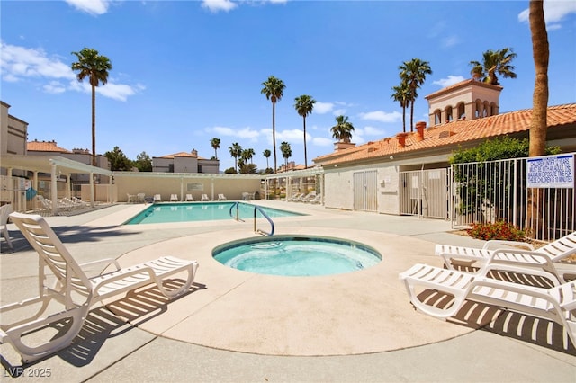 community pool featuring a hot tub, fence, and a patio