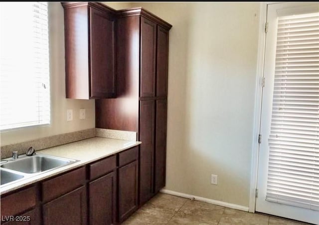 7563 Captain Lord Ct, Las Vegas, NV 89166 - kitchen featuring light countertops, a sink, light tile patterned floors, baseboards, and dark brown cabinets